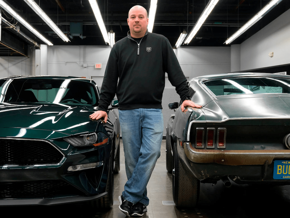 Sean Kiernan avec, à gauche, la Ford Mustang Bullitt de 2019 et, à droite, la Ford Mustang fastback de 1968, celle du film Bullitt sorti en 1968. - courtoisie Ford Motor Company.