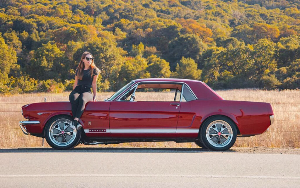 Francesca assise sur le capot de sa Mustang GT 1966 en Californie