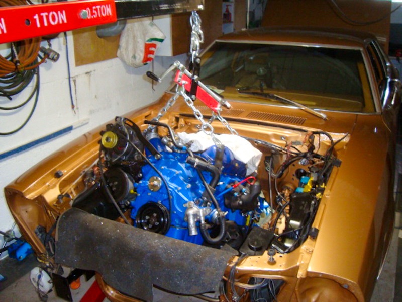 Une étape clé de la restauration : la Mustang retrouve son moteur, soigneusement mis en place à l'aide d'une chèvre d'atelier.