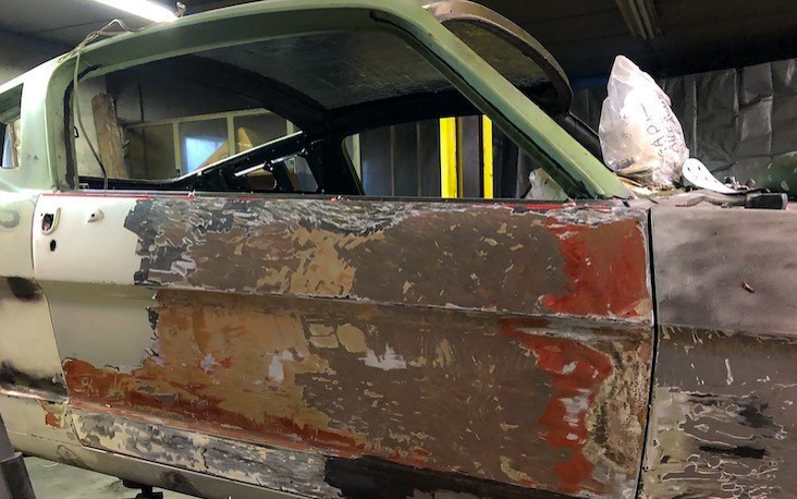 Portière passager laissant apparaître plusieurs anciennes couches de peinture sur une Mustang fastback de 1965.