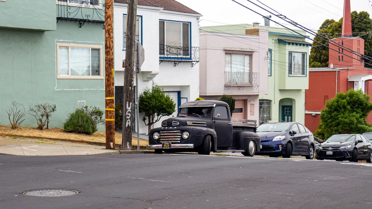 Un vieux pick up Ford tient compagnie à des voitures plus récentes sur le bas côté...