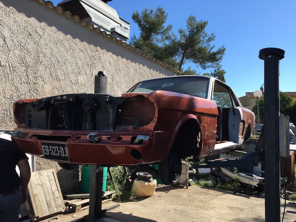 La Mustang est en suspension dans la cour de la carrosserie.