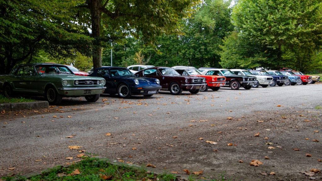Sortie Mustang anciennes Rhône-Alpes – Mustang classiques alignées près du restaurant avec une Porsche