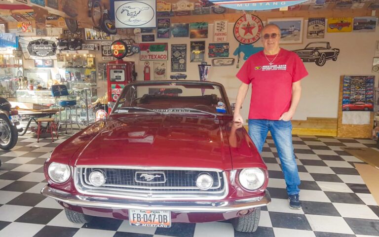 Jacques avec sa Mustang cabriolet 1968 dans son garage rempli d’objets et souvenirs automobiles