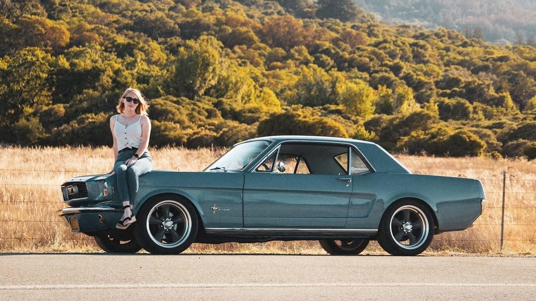Marissa assise sur l'aile avant de sa Mustang.
